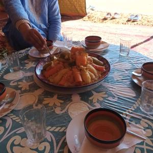 a person sitting at a table with a plate of food at Auberge Aain Nakhla in Guelmim