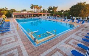 a large swimming pool with blue lounge chairs and sidx sidx sidx at Continental Palace in Psalidi
