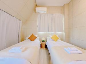 two twin beds in a room with a window at Mori house ookubobiru in Tokyo