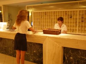 a woman standing at a counter looking in a mirror at Continental Palace in Psalidi