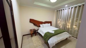 a bedroom with a bed with a green blanket at Upland Estates Serviced Apartments in Lusaka