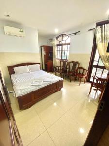 a bedroom with a bed in a room with chairs at LotusHotel 2 in Ho Chi Minh City