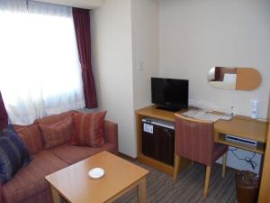 a living room with a couch and a desk with a tv at Spa & Sauna Hotel Hitachi Plaza in Hitachi