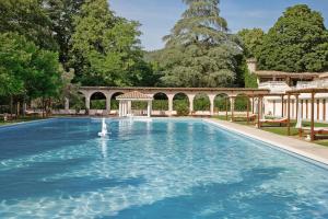 a large swimming pool with a gazebo and trees at Château de Fontager in Serves-sur-Rhône