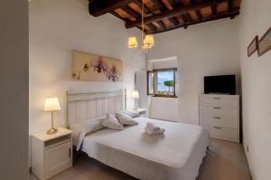 a white bedroom with two beds and a television at Tenuta La Chiusa in Portoferraio