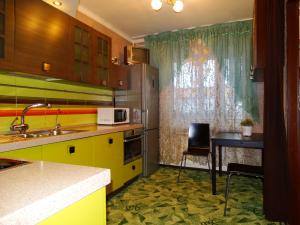モスクワにあるInnDays on Leninskiy prospekt 10のキッチン(黄色のキャビネット、テーブル、椅子付)