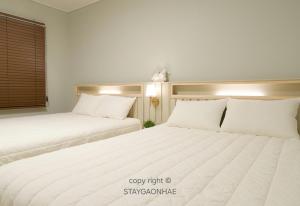 two beds in a room with white sheets and pillows at Stay Gaonhae in Gyeongju
