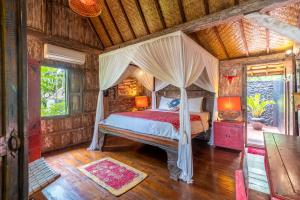 a bedroom with a bed with a canopy at Kai's Beachfront Villa in Gili Islands