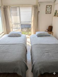 two beds in a room with a window at Blue moon house miyama in Funabashi