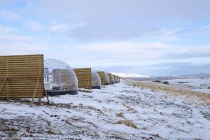 a row of wicker chairs in the snow at Aurora Igloo North in Hvammstangi