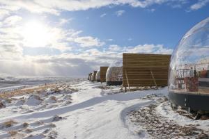 a row of glass domes in the snow at Aurora Igloo North in Hvammstangi