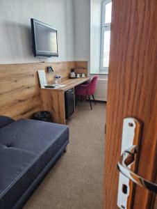 a room with a bed and a desk with a television at Hotel U Labutě in Žďár nad Sázavou