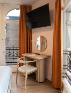 a room with a desk and a mirror and a window at CS Hotel in Amsterdam