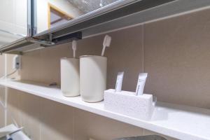 a shelf with three toothbrushes in white holders in a bathroom at 퍼즈스테이 Pause Stay in Chuncheon