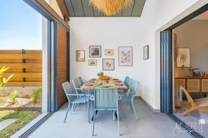 a dining room with a table and blue chairs at VILLA ESCALE TROPICALE - classée 5 in Petite Île