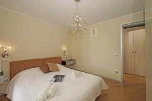 a bedroom with a bed with a book and a chandelier at Apt Il Barcone - Gardagate in Sirmione