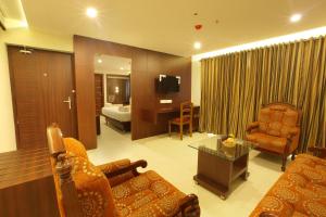 a living room with a couch and a room with a bed at Hotel Indraprastha Thiruvananthapuram in Trivandrum