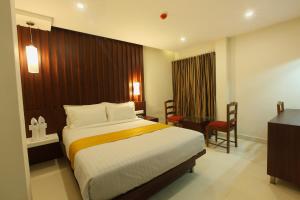 a hotel room with a large bed and a desk at Hotel Indraprastha Thiruvananthapuram in Trivandrum