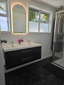 a bathroom with a sink and two mirrors and a shower at Livingstone Retreat in Hokitika
