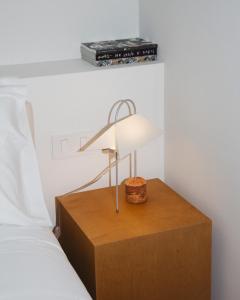 a lamp on a wooden table next to a bed at Casa Teva Rooms Sevilla in Seville