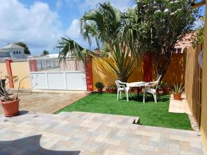 a patio with a table and chairs in a yard at Sunny Isle Apartment in Rooi Master