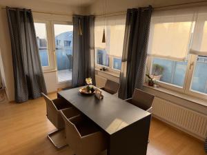 a dining room with a table and chairs and windows at Penthouse Seeblick Wohnung 86 qm KLIMATISIERT in Friedrichshafen