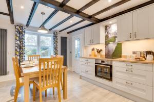 a kitchen with white cabinets and a wooden table and chairs at 3 Bed in Catterick oc-ds934 in Catterick Bridge