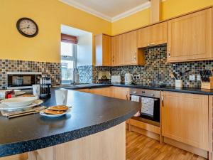 a kitchen with wooden cabinets and a clock on the wall at 1 Bed in Edzell oc-ca335 in Edzell