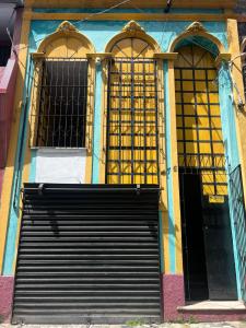 a building with two windows and a black door at Carpe Diem Suítes in Belém