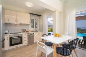 a kitchen and dining room with a table and chairs at Villa Michou Helios by Villa Plus in Lourdata