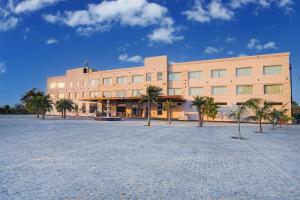 a large building with palm trees in front of it at Sunday Resort & Spa Manesar by CheckIn, Gurugram in Gurgaon