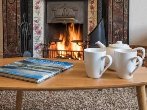 a table with two cups and a book and a fireplace at 6 Bed in Keswick oc-sz044 in Braithwaite +19 photos