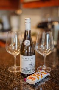 a bottle of wine and two wine glasses on a counter at Central Stellenbosch Apartment with secure parking in Stellenbosch