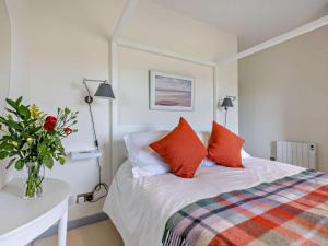 a bedroom with a bed with red pillows and a table at 3 Bed in Arbroath oc-90784 in Inverkeilor