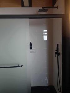 a bathroom with a shower with a white wall at #5 Le Repère Aux Corbeaux in Saint-Onésime