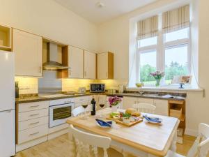 a kitchen with a wooden table and white cabinets at 1 Bed in Langholm oc-83343 in Langholm