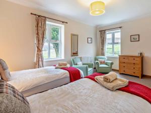 a bedroom with two beds and a chair and windows at 2 Bed in Brechin oc-ca300 in Edzell