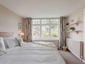 a bedroom with a large white bed and a window at 3 Bed in Gullane oc-96141 in Gullane
