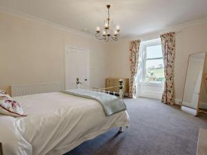 a bedroom with a bed with a chandelier and a window at 3 Bed in Biggar oc-82924 in Biggar
