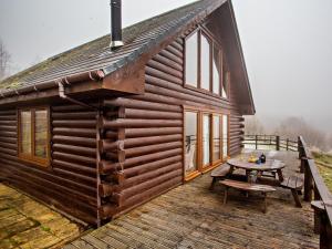 a wooden cabin with a table on a deck at 3 Bed in Fort William oc-95783 in Torlundy