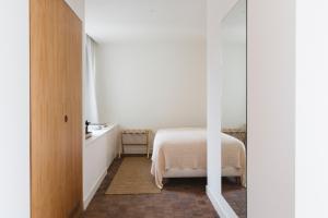 a white bedroom with a bed and a table at Casa Teva Rooms Sevilla in Seville
