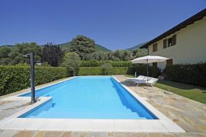 a swimming pool with a chair and an umbrella at Villetta Enzo - Gardagate in Toscolano Maderno