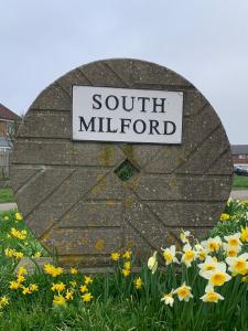 a sign for south millford on a rock with flowers at Park View Guest Suite in South Milford