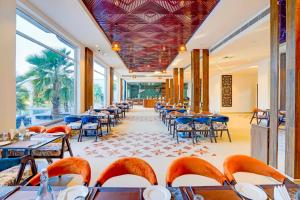 a restaurant with tables and chairs and windows at Sunday Resort & Spa Manesar by CheckIn, Gurugram in Gurgaon