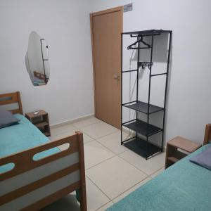 a room with two beds and a glass book shelf at Ap Lagoa da Prata com Ar condicionado in Lagoa da Prata