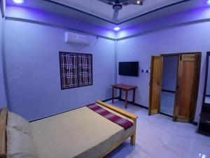 a bedroom with a bed and a table and a tv at AR villa in Jaffna