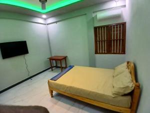 a bedroom with a bed and a tv and a table at AR villa in Jaffna +1 photo