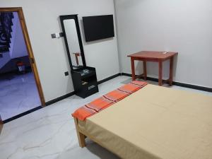 a room with a bed and a table and a television at AR villa in Jaffna