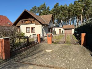 a white house with a gate and a driveway at Ferienhaus Villa Waldblick in Kolkwitz