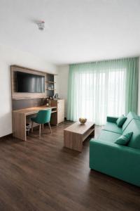 a living room with a couch and a desk with a television at Hotel Rheinpark Rees in Rees